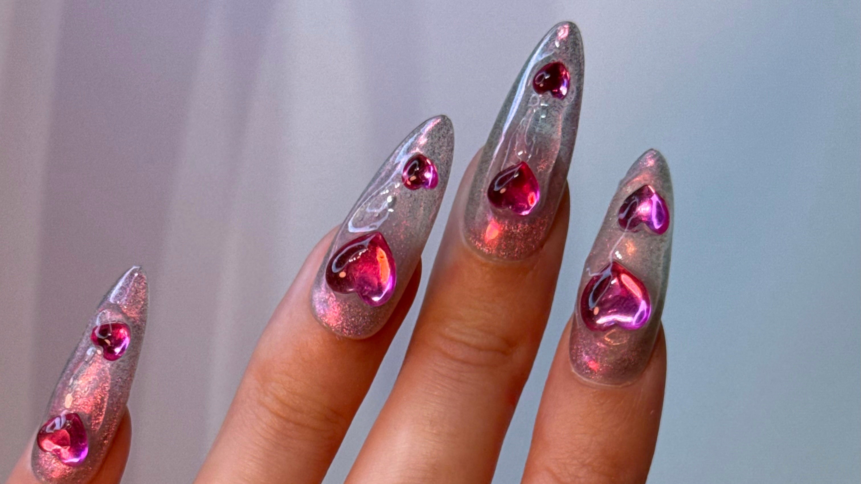 Nails with pink heart-shaped decorations on a neutral background